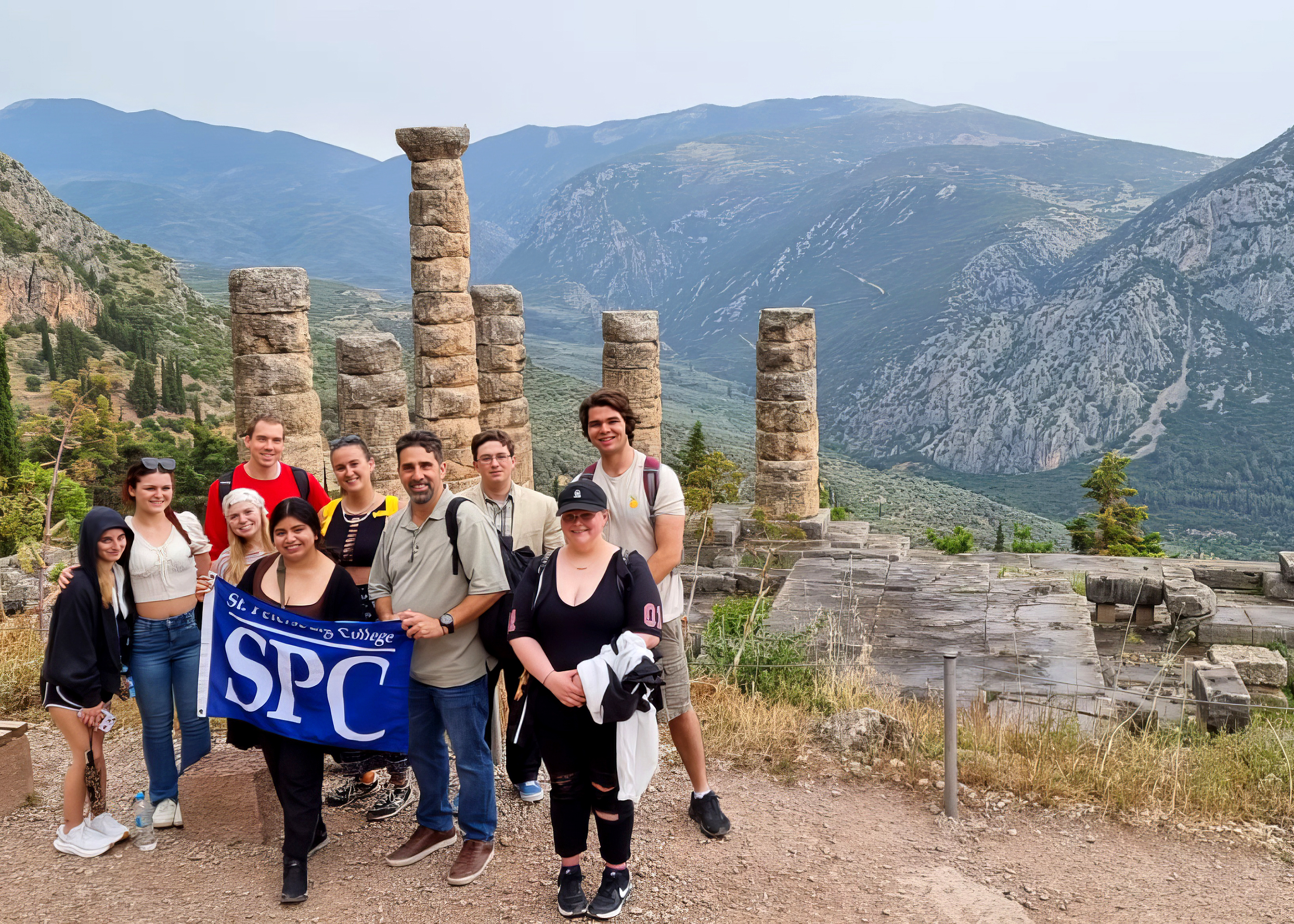 Students holding SPC banner in front of ancient Greek ruins.